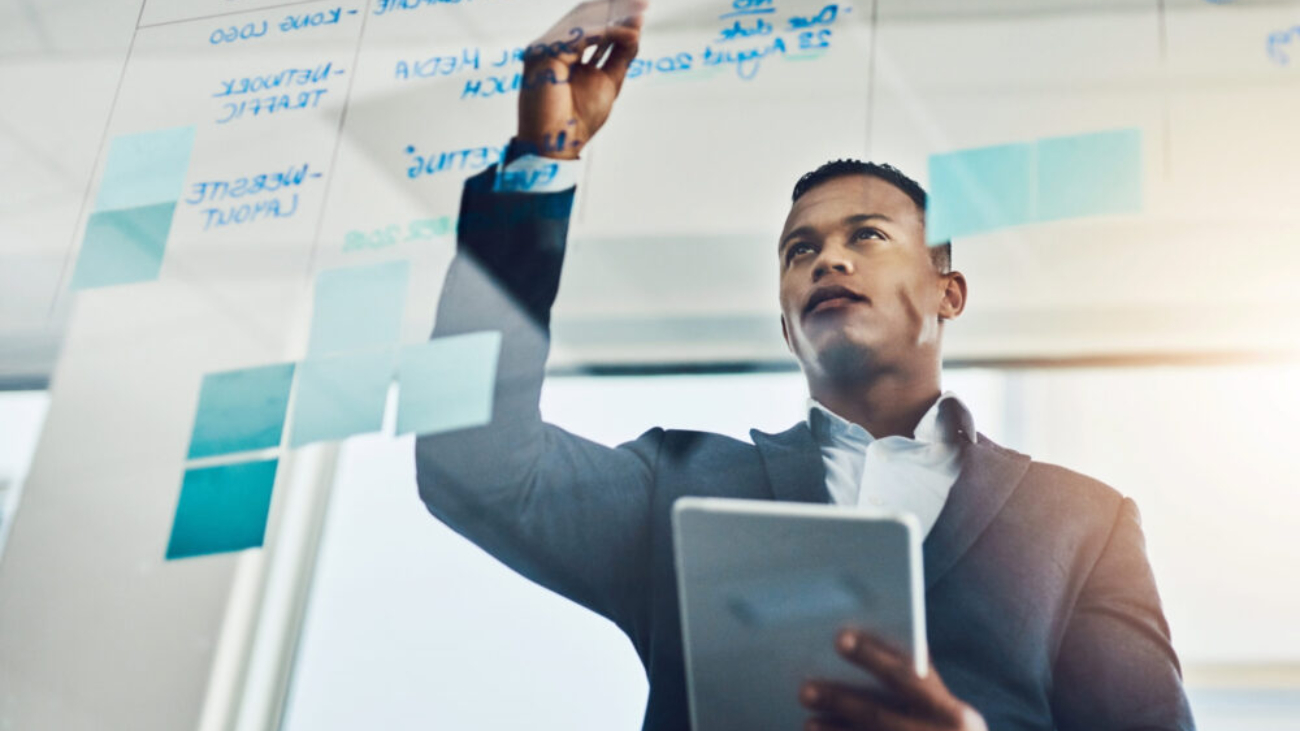 Finance professional in a modern Dublin office planning strategy on a glass board with a tablet in hand, symbolising the real-time insights and NetSuite ERP benefits driving business growth in Ireland.