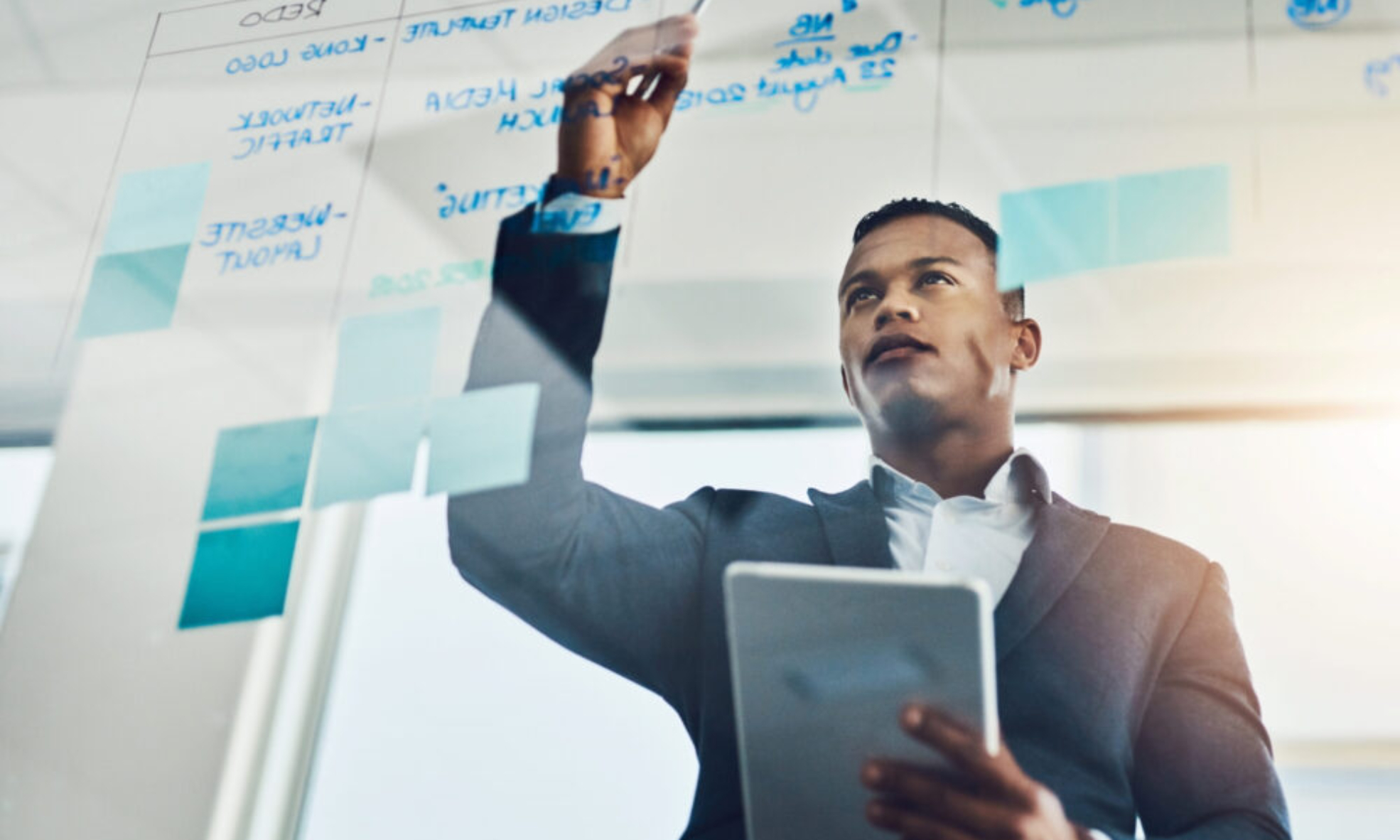 Finance professional in a modern Dublin office planning strategy on a glass board with a tablet in hand, symbolising the real-time insights and NetSuite ERP benefits driving business growth in Ireland.