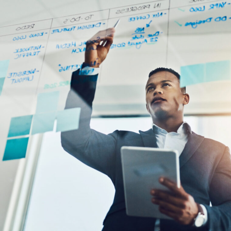 Finance professional in a modern Dublin office planning strategy on a glass board with a tablet in hand, symbolising the real-time insights and NetSuite ERP benefits driving business growth in Ireland.