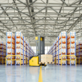 Modern warehouse with automated forklift and organised shelving, representing an advanced warehouse management system in Ireland for wholesale distributors.