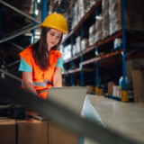 Warehouse employee using a laptop to monitor stock levels – showcasing NetSuite ERP benefits for smarter inventory management in a modern distribution centre.