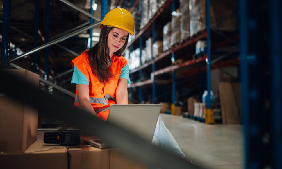 Warehouse employee using a laptop to monitor stock levels – showcasing NetSuite ERP benefits for smarter inventory management in a modern distribution centre.