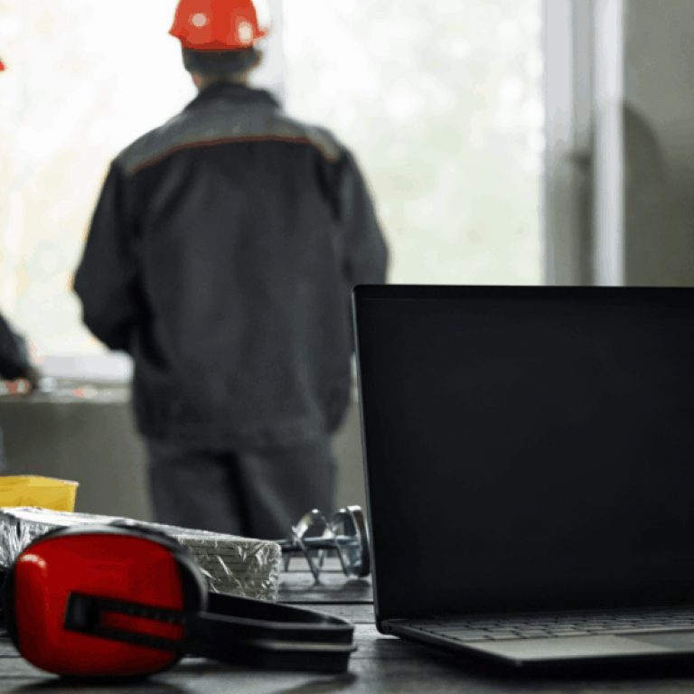 Two middle-aged men reviewing a project beside a laptop displaying field service management software