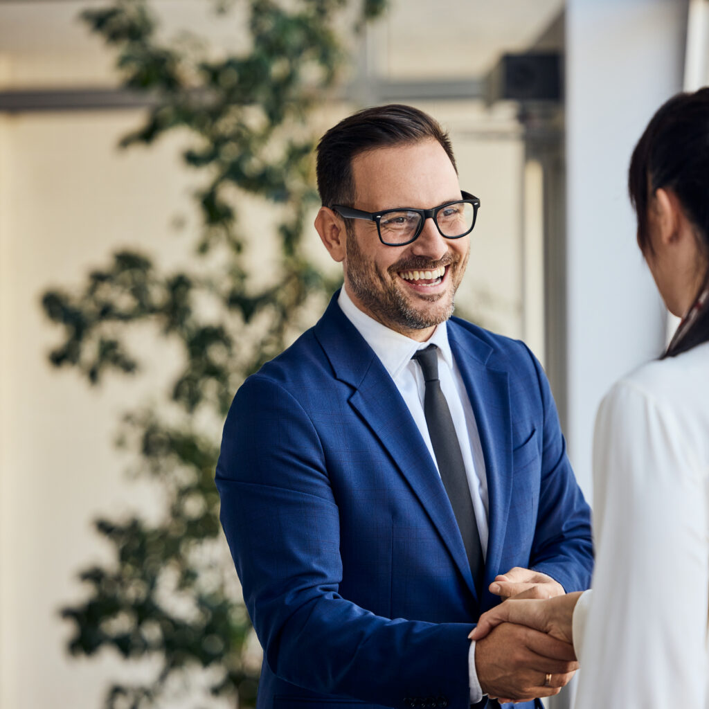 Business partners shaking hands in a bright modern office during a NetSuite Ireland implementation planning meeting.